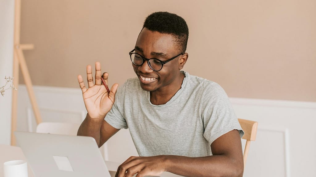 Man sitting at his computer waving to his men's therapist as he starts an online counseling session